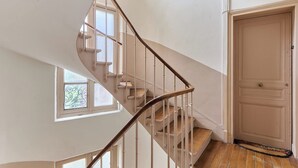 Eine Wendeltreppe mit weißen Geländern und Holzstufen, die zu einer Zwischenebene führen.