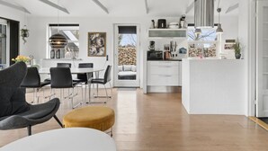 Una cocina moderna con armarios blancos, horno empotrado y una lámpara colgante.