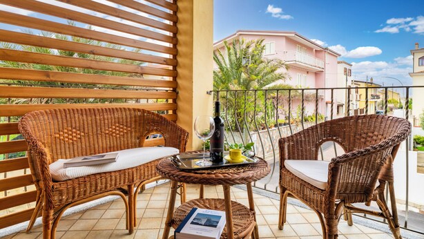 Un balcon avec des meubles en osier, une bouteille et un verre.