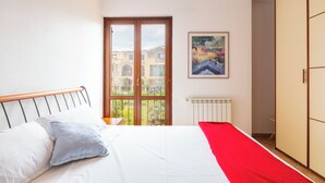 Une chambre à coucher avec un lit, une fenêtre, un radiateur et un tableau accroché au mur.