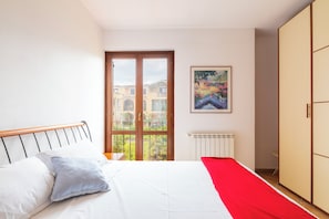 Ein Schlafzimmer mit Bett, Fenster, Heizkörper und einem Bild an der Wand.