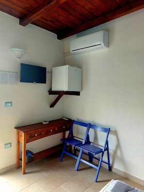 A room with a wooden desk, a blue chair, an air conditioner, and a ceiling fan. - Oltremare - Camera BLU (Vignacastrisi)