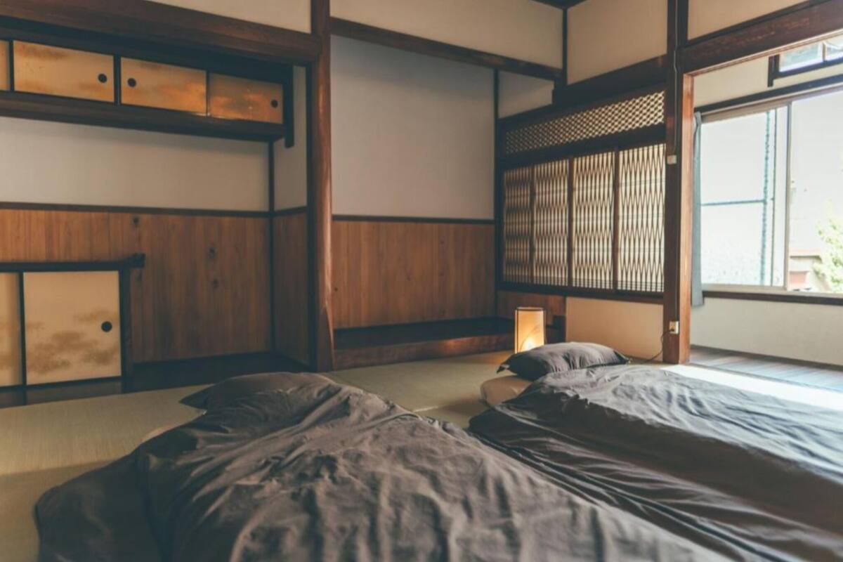 A traditional Japanese-style room with tatami flooring, a low wooden bed, and a sliding door.