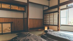 Une pièce de style japonais traditionnel, avec un sol recouvert de tatamis, un lit bas en bois et une porte coulissante.