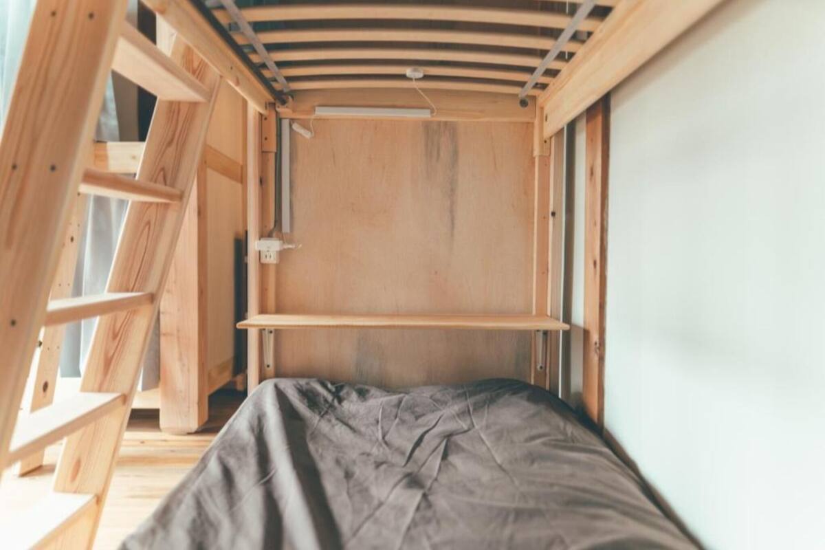 A small, compact room with a bunk bed, wooden walls, and a slanted ceiling.