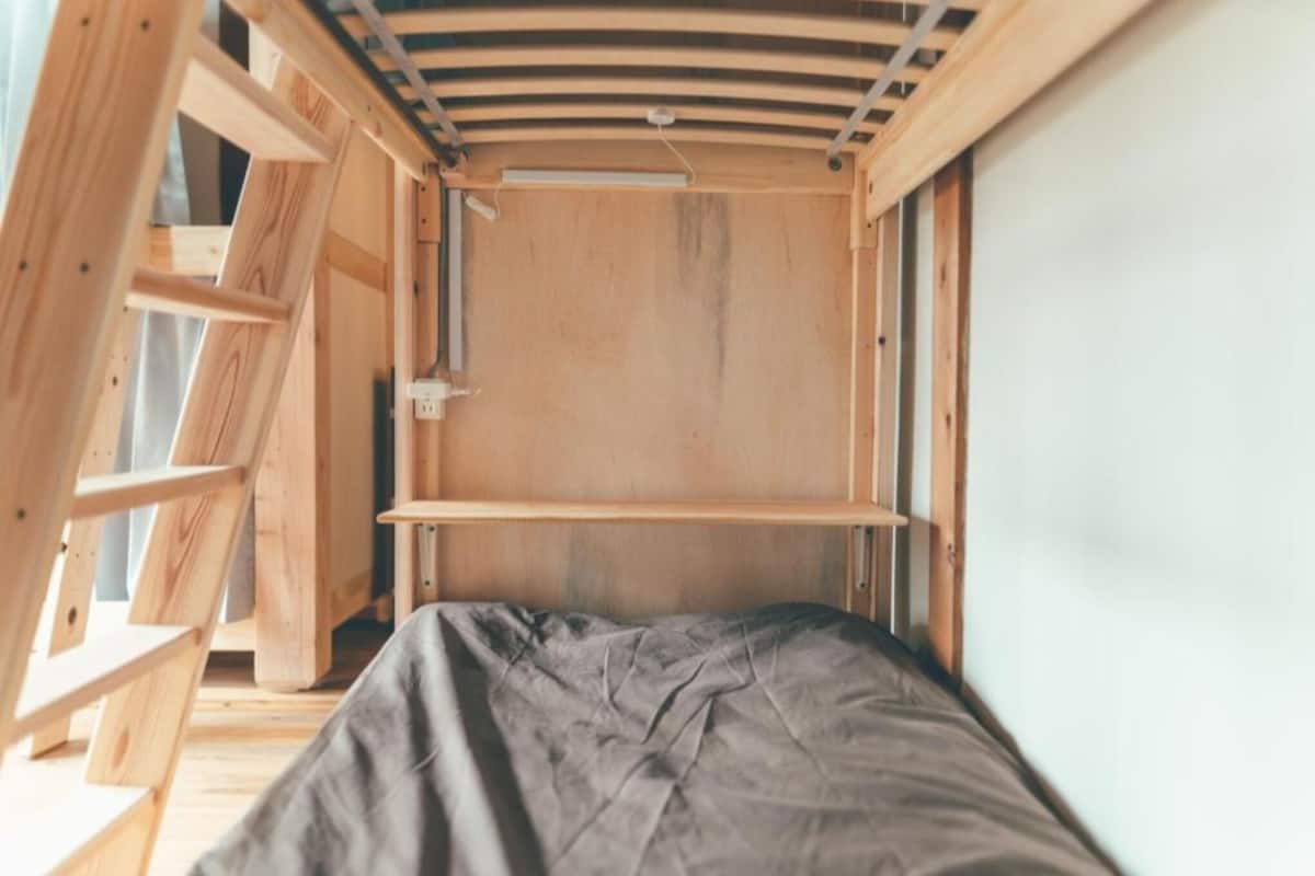 A small, compact room with a bunk bed, wooden walls, and a slanted ceiling.