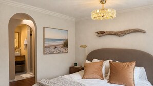 Een slaapkamer met een bed, een kroonluchter, een schilderij en een houten decoratie.