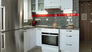 Et moderne køkken med stålemmer, hvide skabe og en backsplash i rød og grå farve.