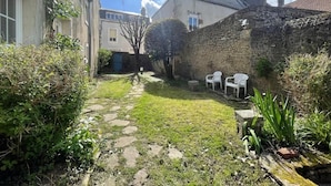A stone wall, a grassy courtyard, and a building with a door. - 3-bedroom apartment in the heart of the Alpes Mancelles, 20 minutes from the 24h of Le Mans (Beaumont-sur-Sarthe)