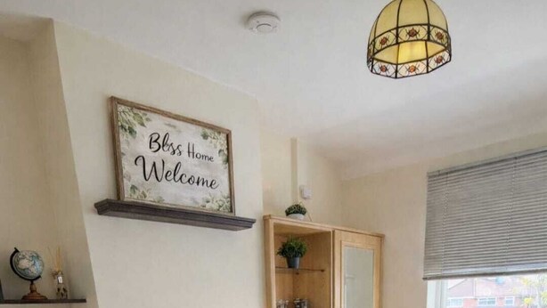 Een netjes ingerichte slaapkamer met een bed, een bureau, een stoel, een nachtkastje, een lamp, een spiegel, een raam met zonwering en een wereldbol aan de muur.