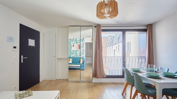 A modern apartment with a dining area, a living room with a sofa, a balcony with a view, and a sliding door leading to another room. - Charming Apartement Boulogne Billancourt Center (Boulogne-Billancourt)