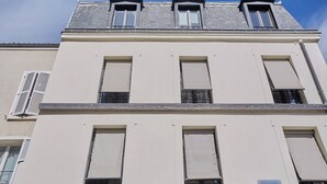 A multi-story building with a flat facade, large windows, and a visible air conditioning unit on the left side. - Charming Apartement Boulogne Billancourt Center (Boulogne-Billancourt)