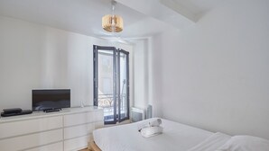 A modern bedroom with a bed, a TV, a dresser, and a window with a view. - Charming Apartement Boulogne Billancourt Center (Boulogne-Billancourt)