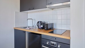 A compact kitchen with a dishwasher, a coffee maker, and a toaster on the countertop. - Charming Apartement Boulogne Billancourt Center (Boulogne-Billancourt)