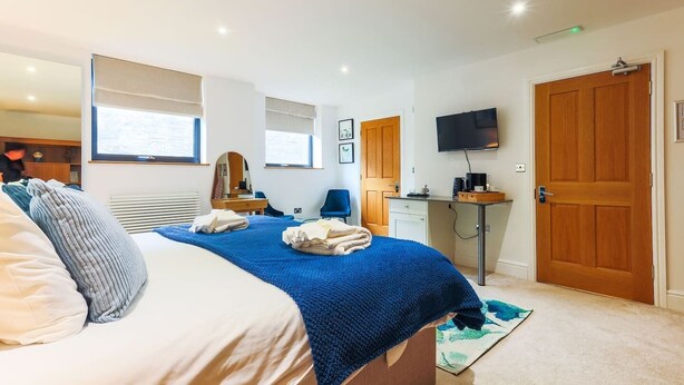 A bedroom with a bed, a desk, a chair, a television, and a door. - Boutique King Suite - Penarth (Vale of Glamorgan)
