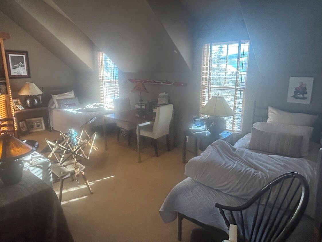 Een slaapkamer met een bed, een bureau, een stoel, een lamp en een raam.