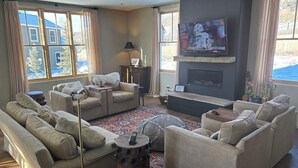 Una sala de estar con chimenea, sofás, una mesa de centro y un televisor.