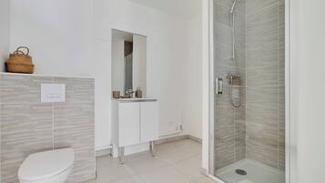 Un baño moderno con inodoro, lavamanos y ducha.
