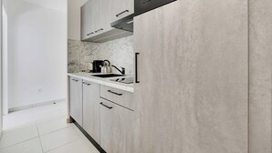 Una cocina moderna con gabinetes grises, una campana extractora de acero inoxidable y un salpicadero de mármol.