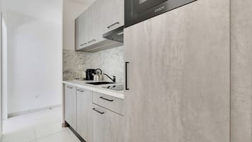 Una cocina moderna con gabinetes grises, una campana extractora de acero inoxidable y un salpicadero de mármol.