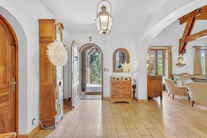 Un couloir avec des portes en bois, une commode en bois, une lampe et un lit à baldaquin.