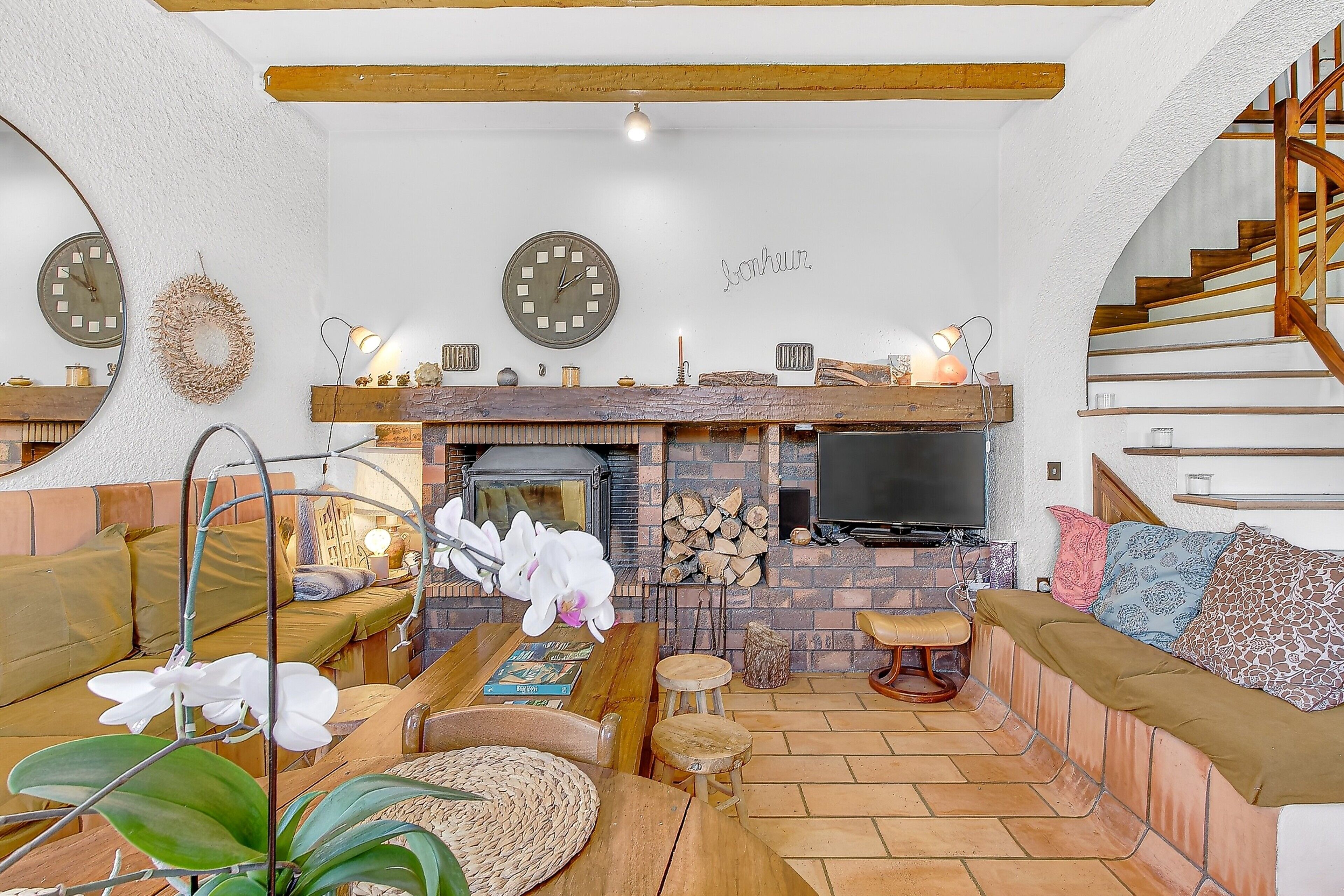 A cozy living room with a fireplace, wooden furniture, and a staircase.