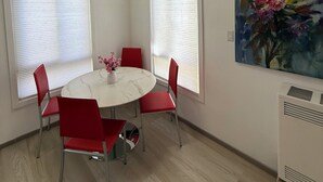 A dining area with a round table, red chairs, a vase with flowers, and a painting on the wall. - Elegant Monet Studio Apartment (Los Angeles)