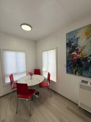 Ein Essbereich mit einem runden Tisch, roten Stühlen, einer Blumenvase und einem Bild an der Wand.