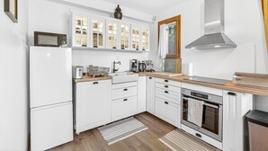 A modern kitchen with white cabinetry, a built-in oven, a microwave, and a stainless steel range hood. - Le Domaines Des Thermes – T2 with Shared Pool, Peaceful Setting, Mountain View (Gap)