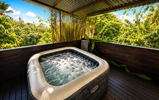 A hot tub on a wooden deck with a view of lush greenery.