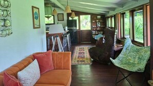 A living room with a sofa, chairs, a dining area, and a kitchen in the background. - Maison Ylang avec Bungalow Uturoa (Raiatea)