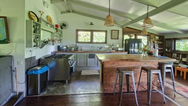 A kitchen with a central island, bar stools, and hanging pendant lights. - Maison Ylang avec Bungalow Uturoa (Raiatea)