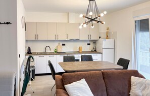 Una cocina moderna con armarios blancos, una mesa de comedor y un sofá marrón.