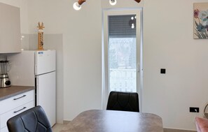 A modern kitchen with a refrigerator, a blender, and a dining table with chairs.