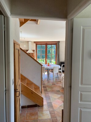 A staircase leading to a dining area with a table and chairs, a window with curtains, and a tiled floor. - The kerdrein house (Telgruc-sur-Mer)