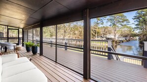 Eine überdachte Terrasse im Freien mit Blick auf einen Fluss, Holzboden und Sitzmöglichkeiten im Freien.