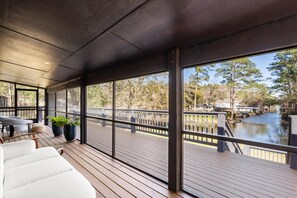 Een overdekt terras buiten met uitzicht op een rivier, houten vloer en zitplaatsen.