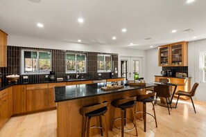 Een moderne keuken met een centraal eiland, houten kastjes en een bar voorzien van krukken.