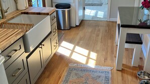A modern kitchen with a built-in sink, a white refrigerator, and a wooden countertop. - Farmhouse on a River (South Kingstown)