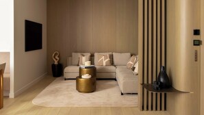 Un salon moderne avec un canapé d’angle, une table basse ronde et un style de décoration minimaliste.