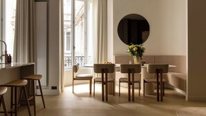 Un intérieur moderne avec un coin repas, des tabourets de bar et un grand miroir rond au mur.
