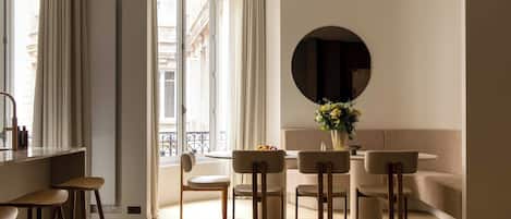 Un intérieur moderne avec un coin repas, des tabourets de bar et un grand miroir rond au mur.