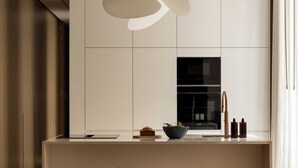 Une cuisine moderne dotée d’un îlot central, de tabourets, d’un luminaire suspendu et offrant une vue sur l’extérieur.