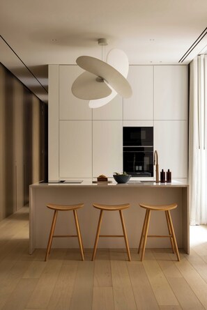 A modern kitchen with a central island, stools, a hanging light fixture, and a view of the outdoors. - Luxury Flat -2br/6p- Madeleine/saint Honore (Paris)