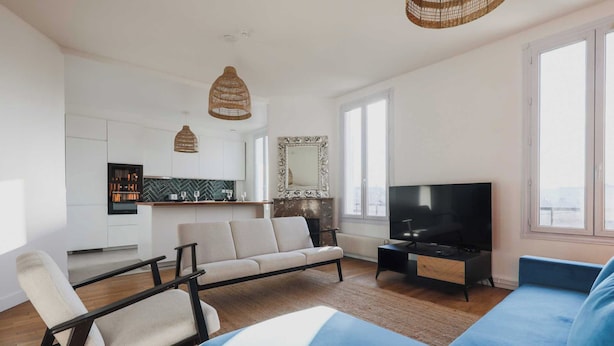 A modern living room with a sofa, TV, and a kitchen in the background. - Magnificent Apartment -2br-6p- Saint-denis (Saint-Denis)