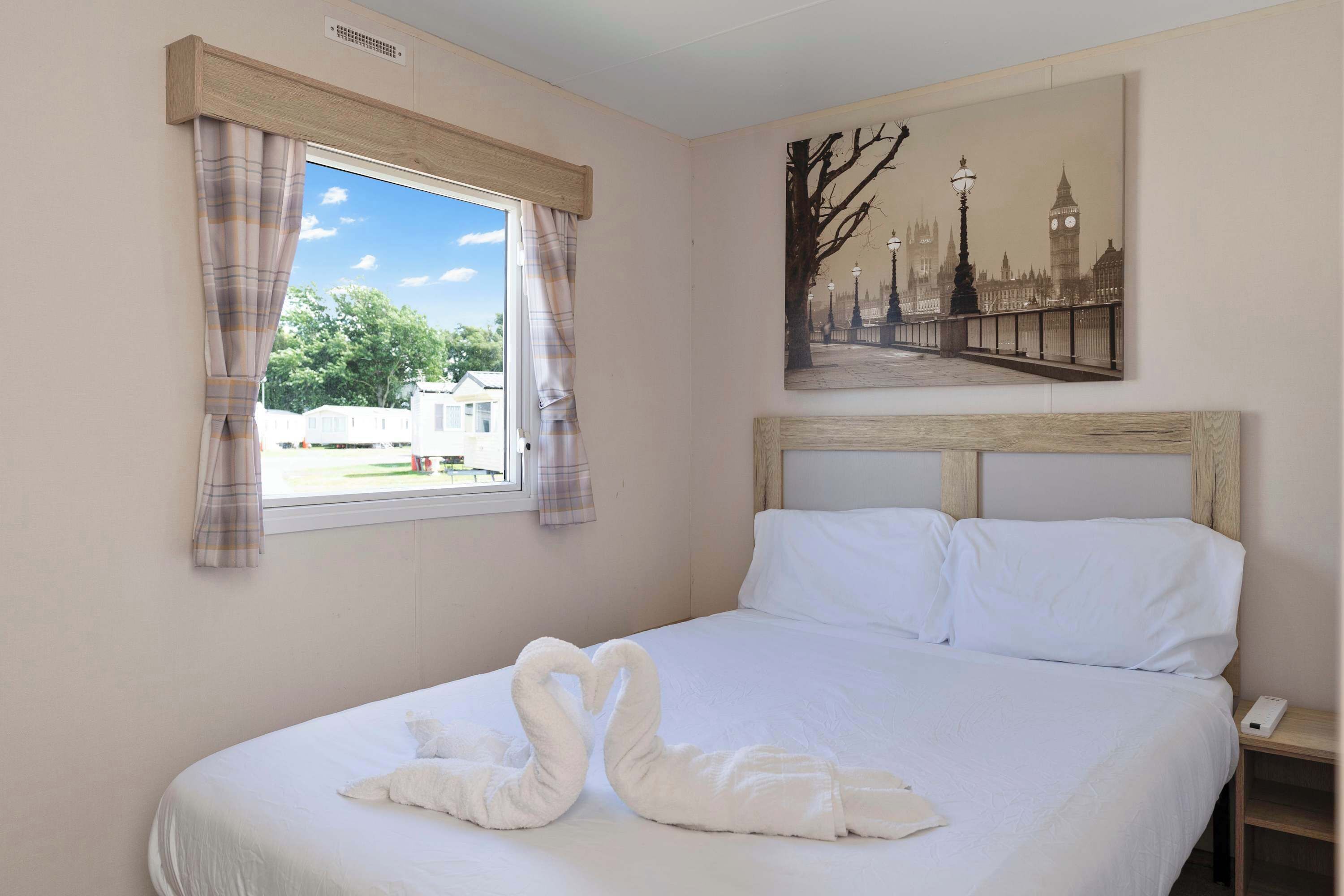 Ein Hotelzimmer mit Bett, einem fenster mit Vorhängen, einem Stadtbildgemälde und einem Nachttisch.