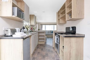 A compact kitchen with wooden cabinets, a microwave, a stove, and a sink.