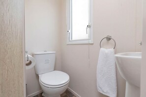 Ein kleines, sauberes Badezimmer mit Toilette, Waschbecken und Handtuchhalter.