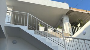 Eine weiße Treppe mit Metallgeländern, die zu einem Balkon führt.