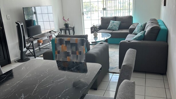 Ein modernes Wohnzimmer mit Esstisch, Sofa und Fernseher.